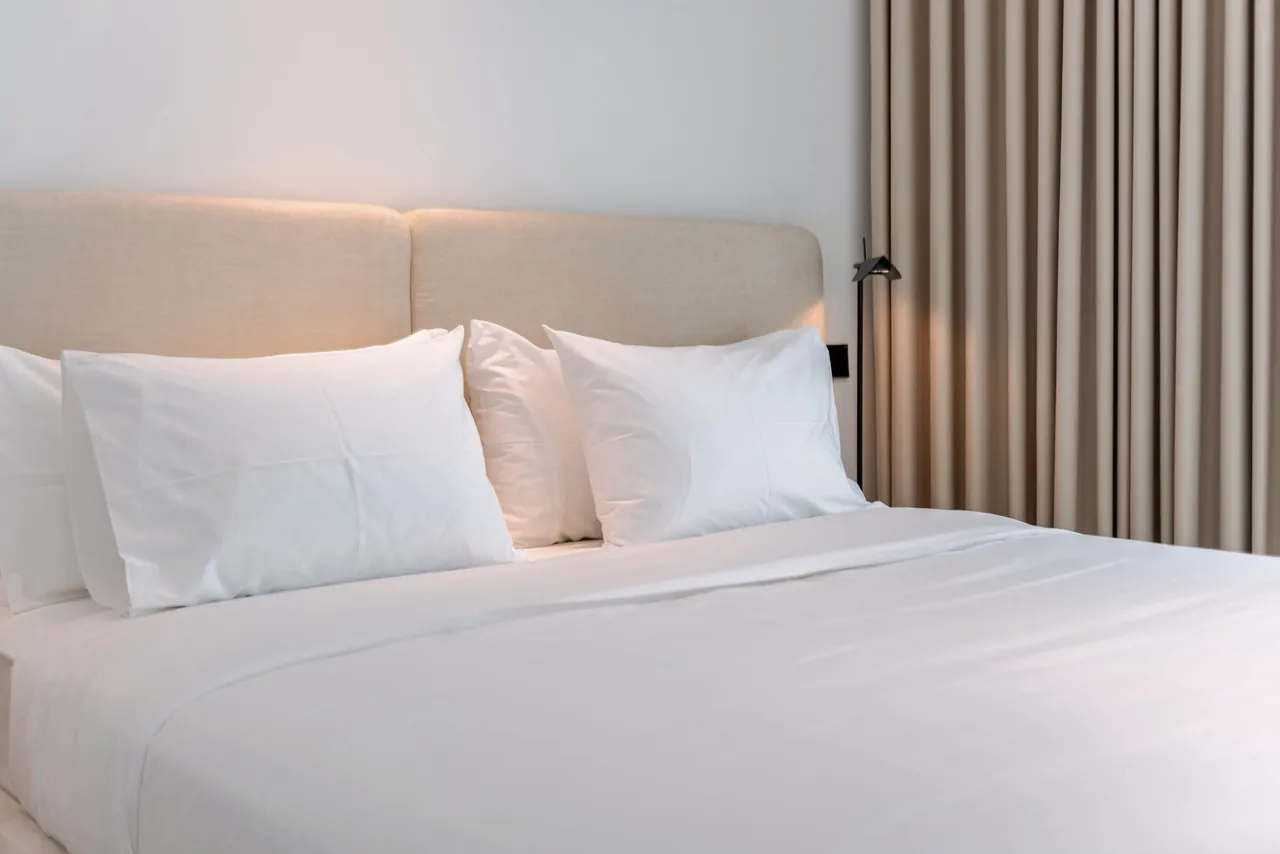 Hotel bed made up in white with four pillows