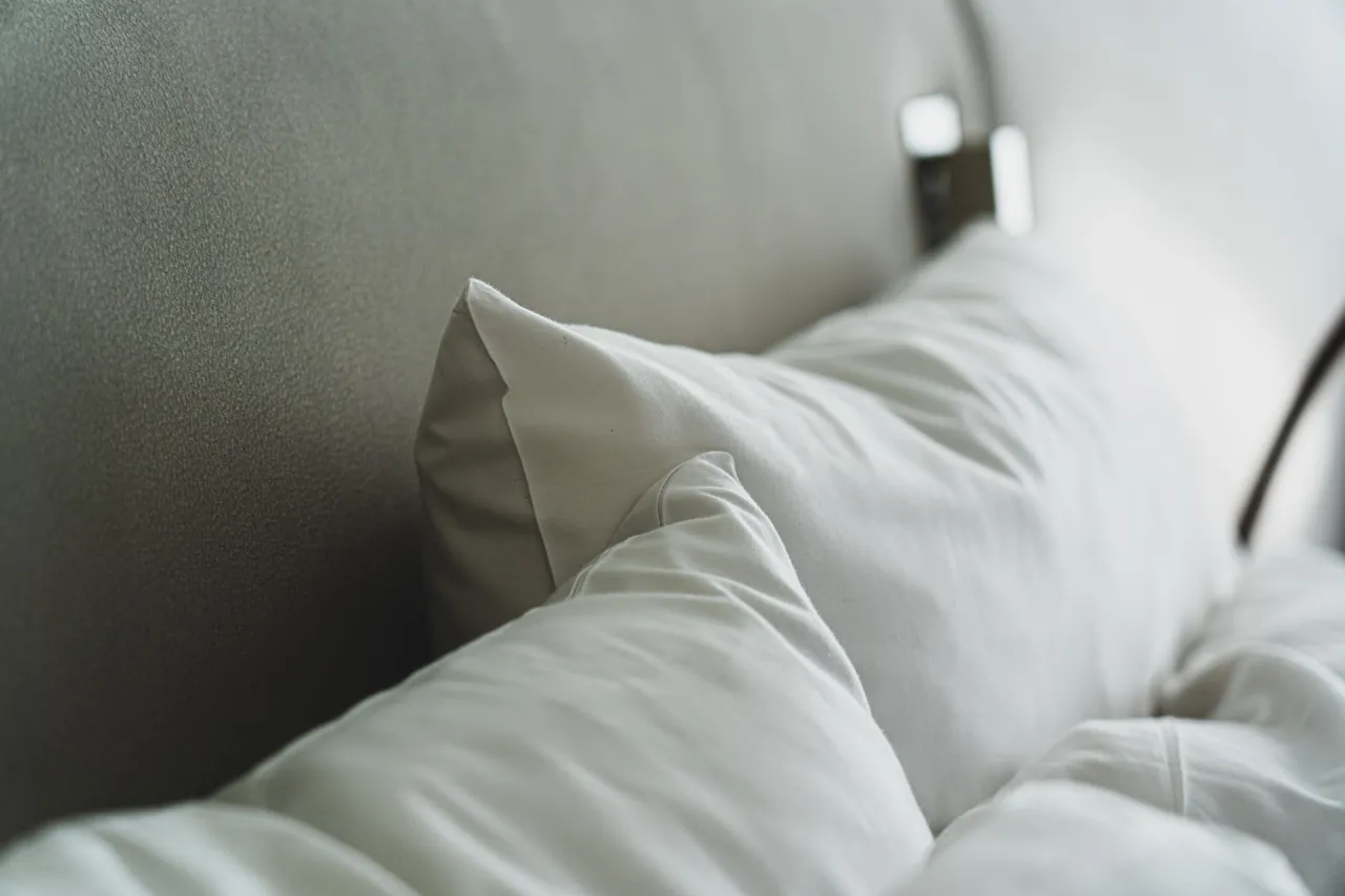 White pillows and a duvet against an upholstered headboard