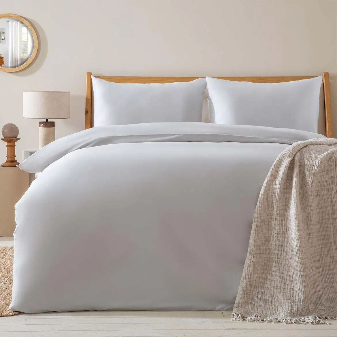 Bed dressed in a white duvet cover set with a beige throw