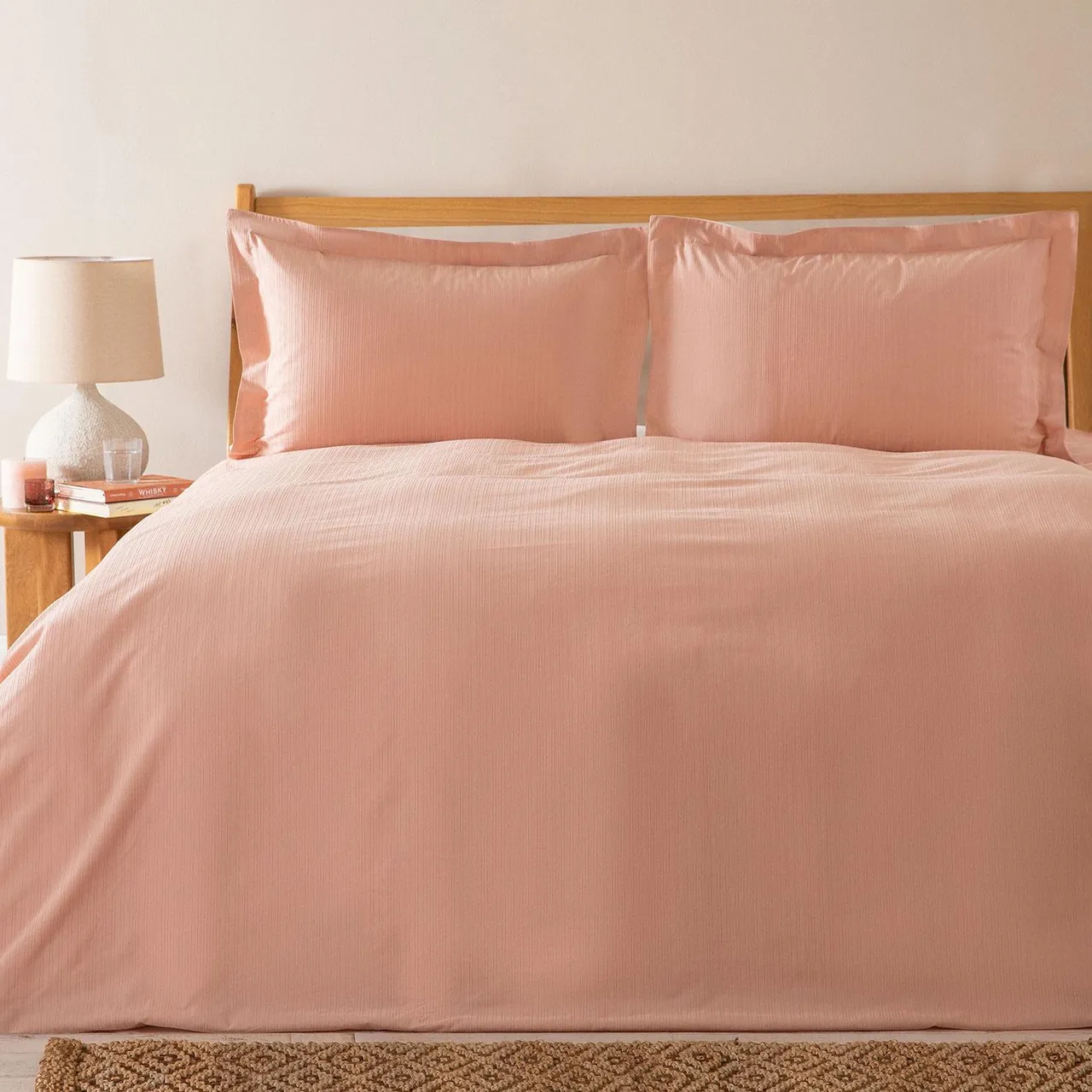 Bed dressed in a salmon pink duvet cover set